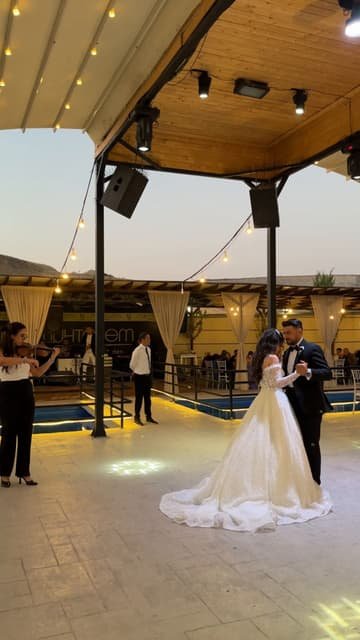 Ahşap çardağın altında ilk dansını eden gelin ve damat; solda canlı keman çalan Aneva müzisyeni